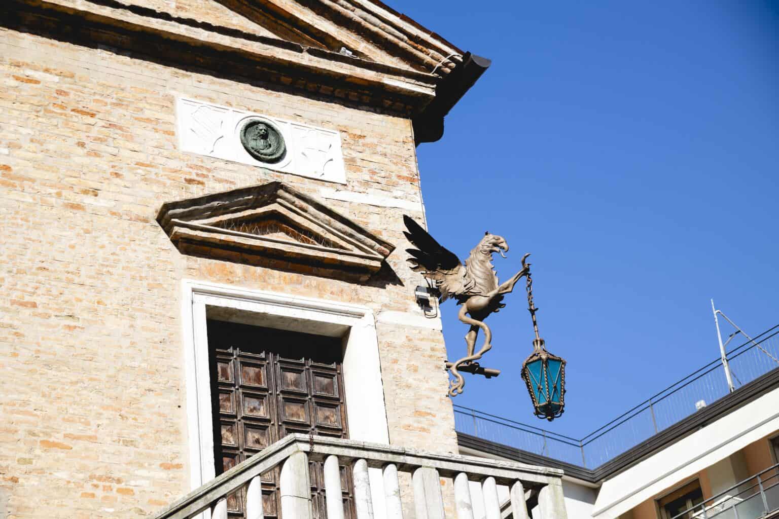 Grifone in ferro battuto che regge una lampada sulla facciata della Provvederia